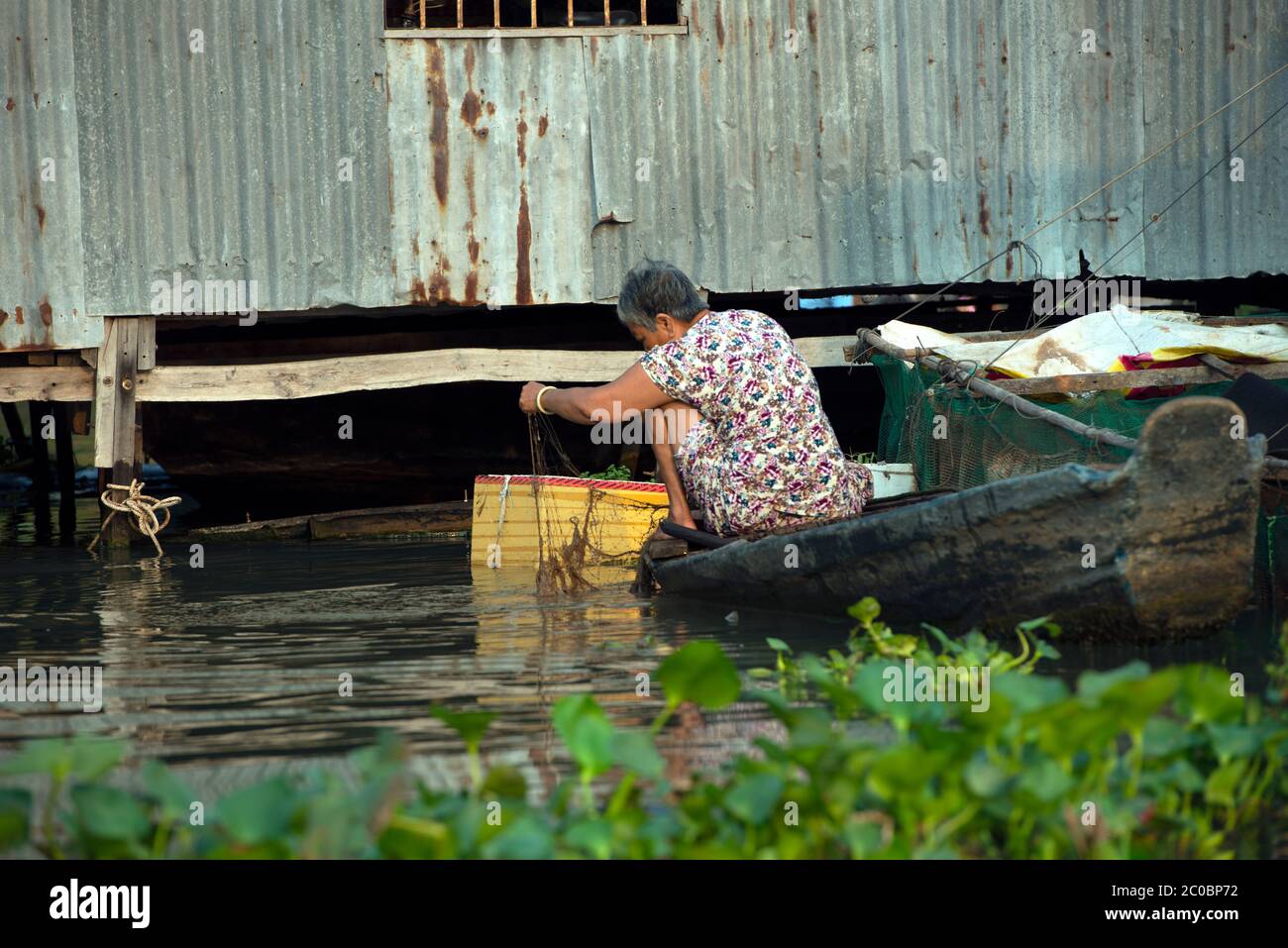 Une femme vietnamienne qui pose son filet de pêche à Chau Doc, dans la région du delta du Mékong, dans le sud du Vietnam. Banque D'Images