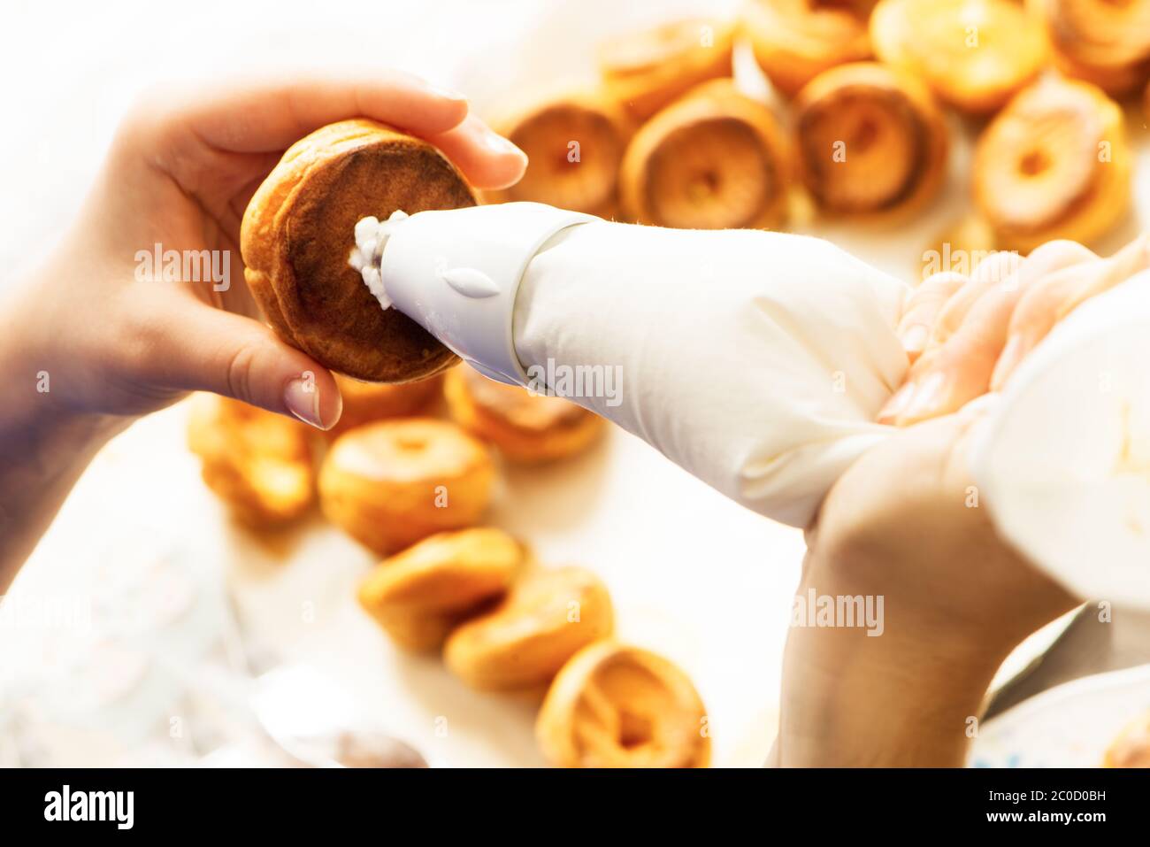 remplir la pâte de profiterolle de crème à l'aide du sachet de pâtisserie de préparation faite maison Banque D'Images