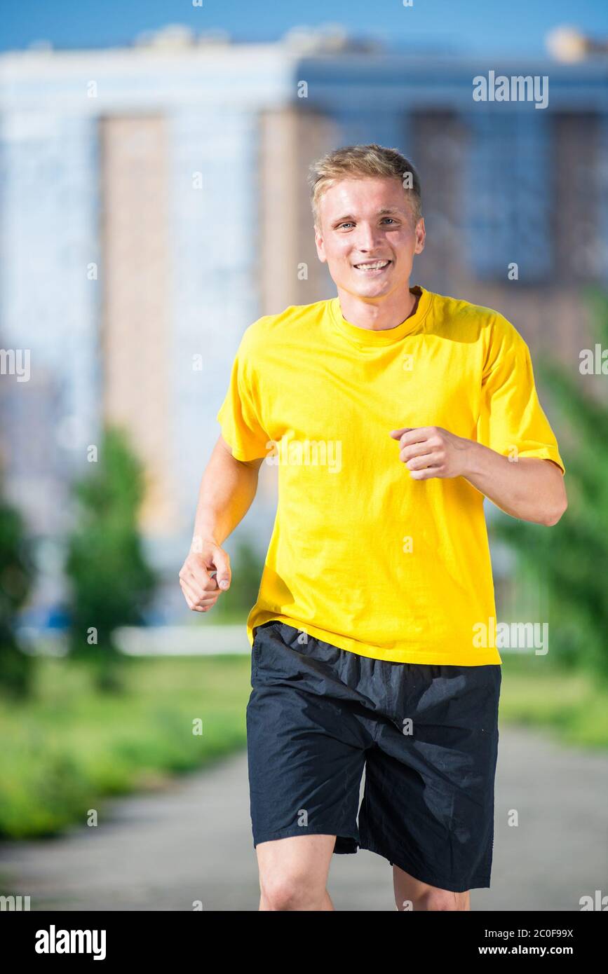 Sporty man jogging in city street park. Remise en forme en plein air. Banque D'Images