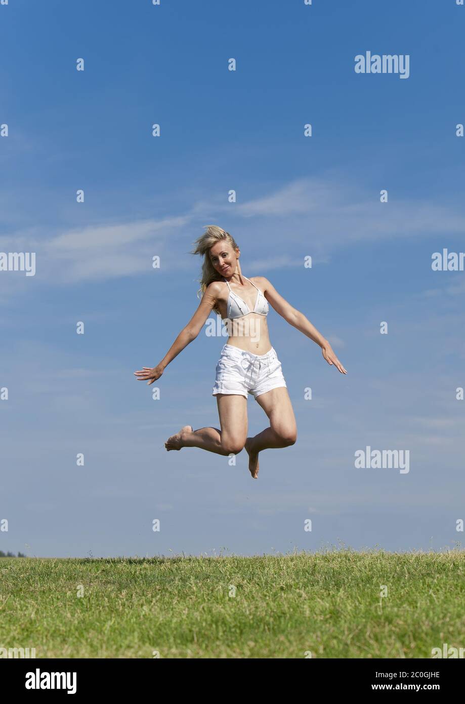 Happy woman in bikini blanc et shorts sauts en une Banque D'Images