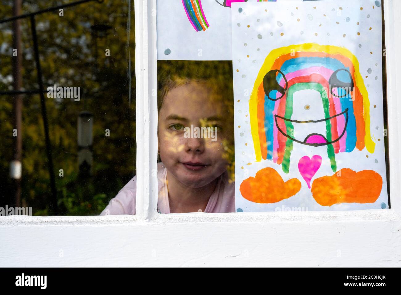 Fille de 8 ans regardant par la fenêtre pendant le verrouillage du coronavirus Banque D'Images