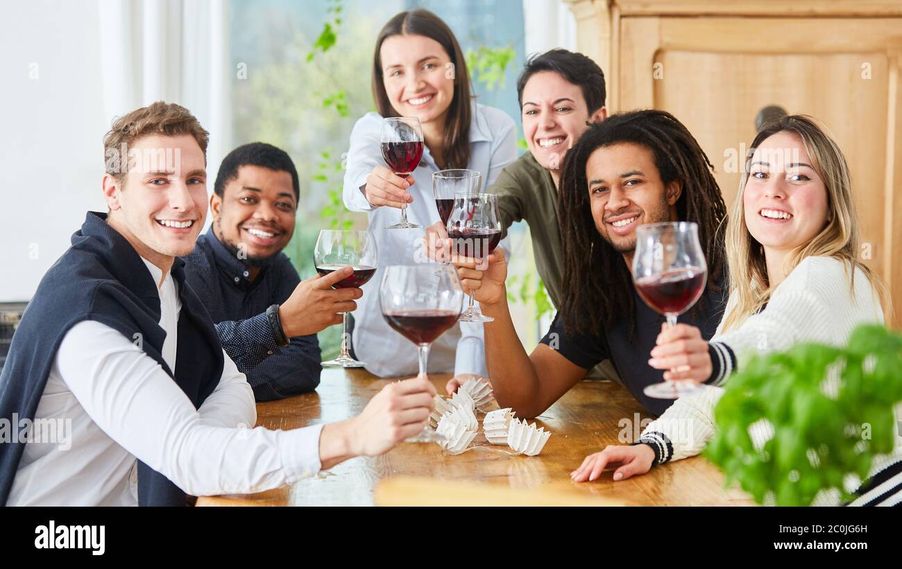 Des amis heureux fêtant à la maison avec un verre de vin à la main Banque D'Images