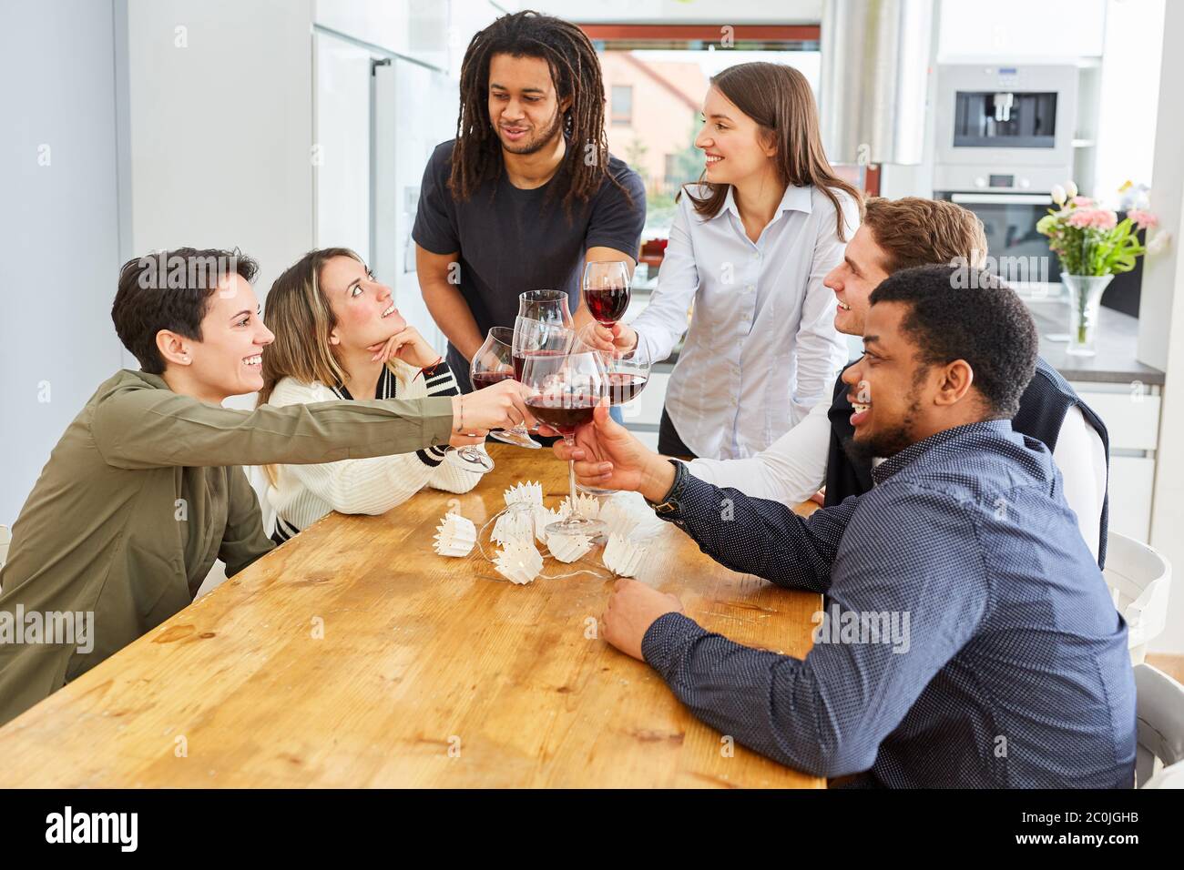 Des amis heureux en dégustant un verre de vin rouge dans la cuisine et en célébrant Banque D'Images