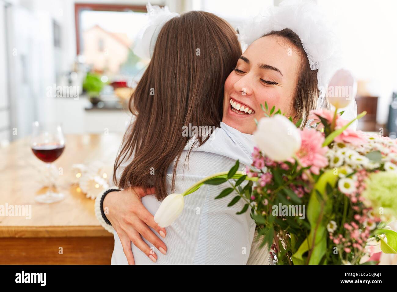 La petite amie félicite Brau avec un voile de mariée à Hochzait avec un câlin et un bouquet de fleurs Banque D'Images