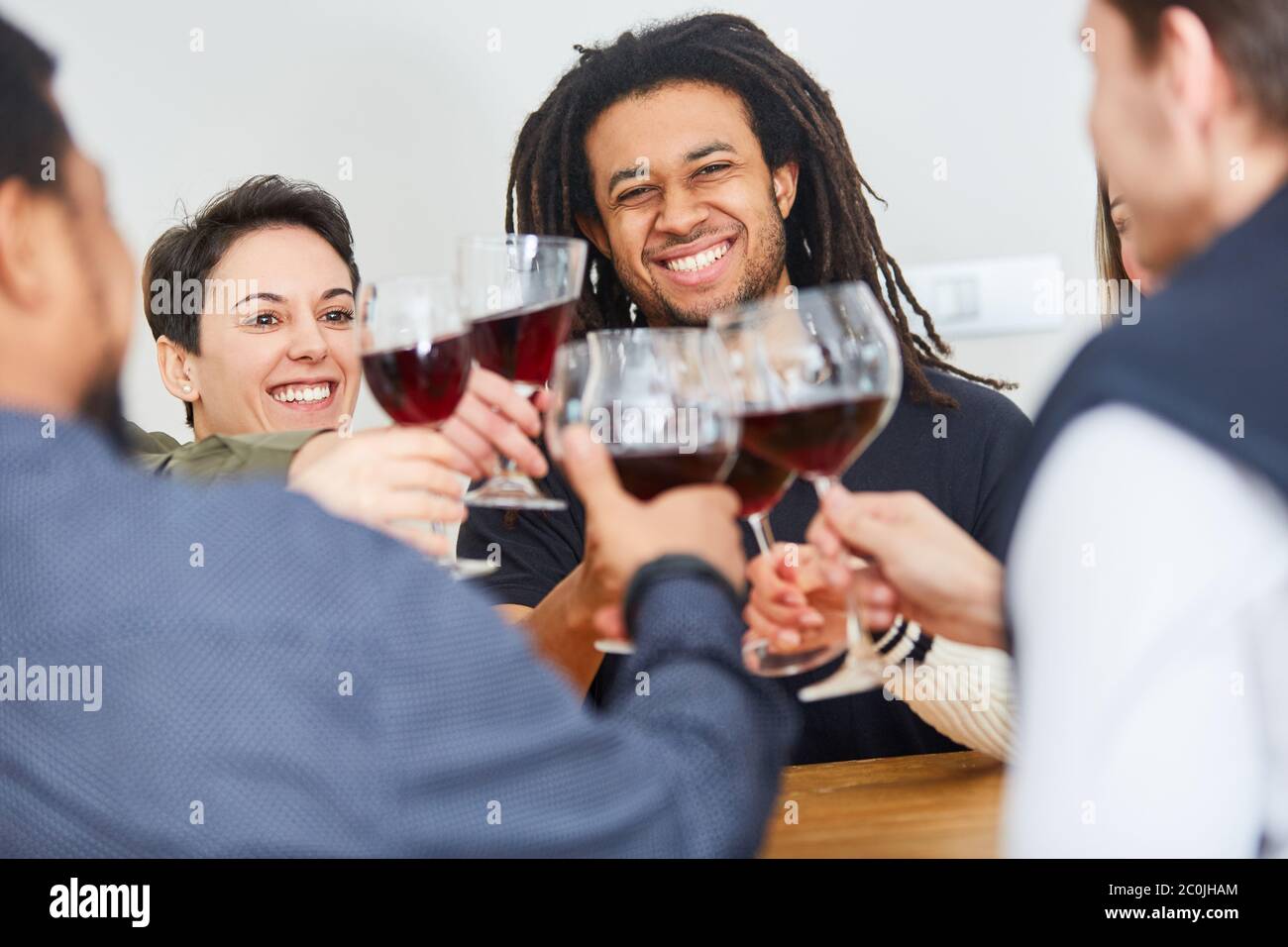 Un groupe d'amis heureux se fait griller avec un verre de vin rouge à la maison Banque D'Images