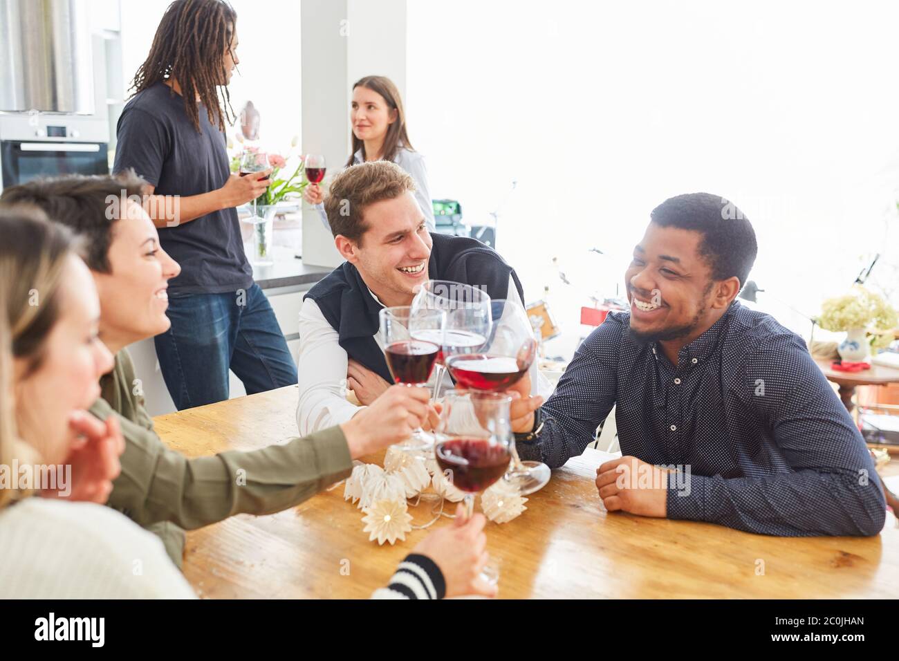 Les élèves qui rient boivent du vin ensemble à la maison dans une cuisine commune Banque D'Images