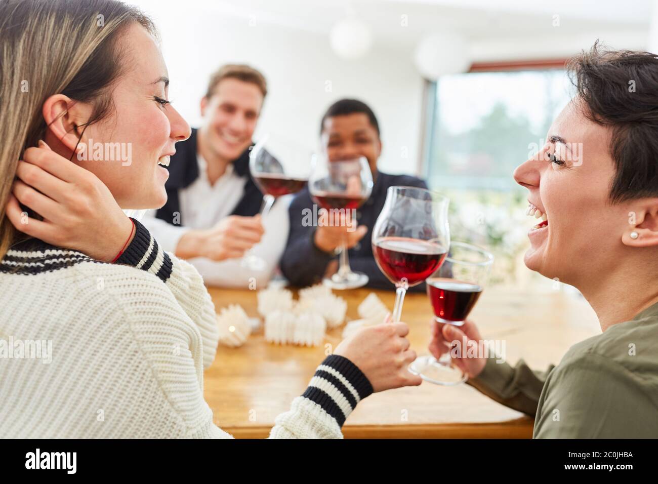 Des amis qui rient se toastent avec un verre de vin rouge à la maison Banque D'Images
