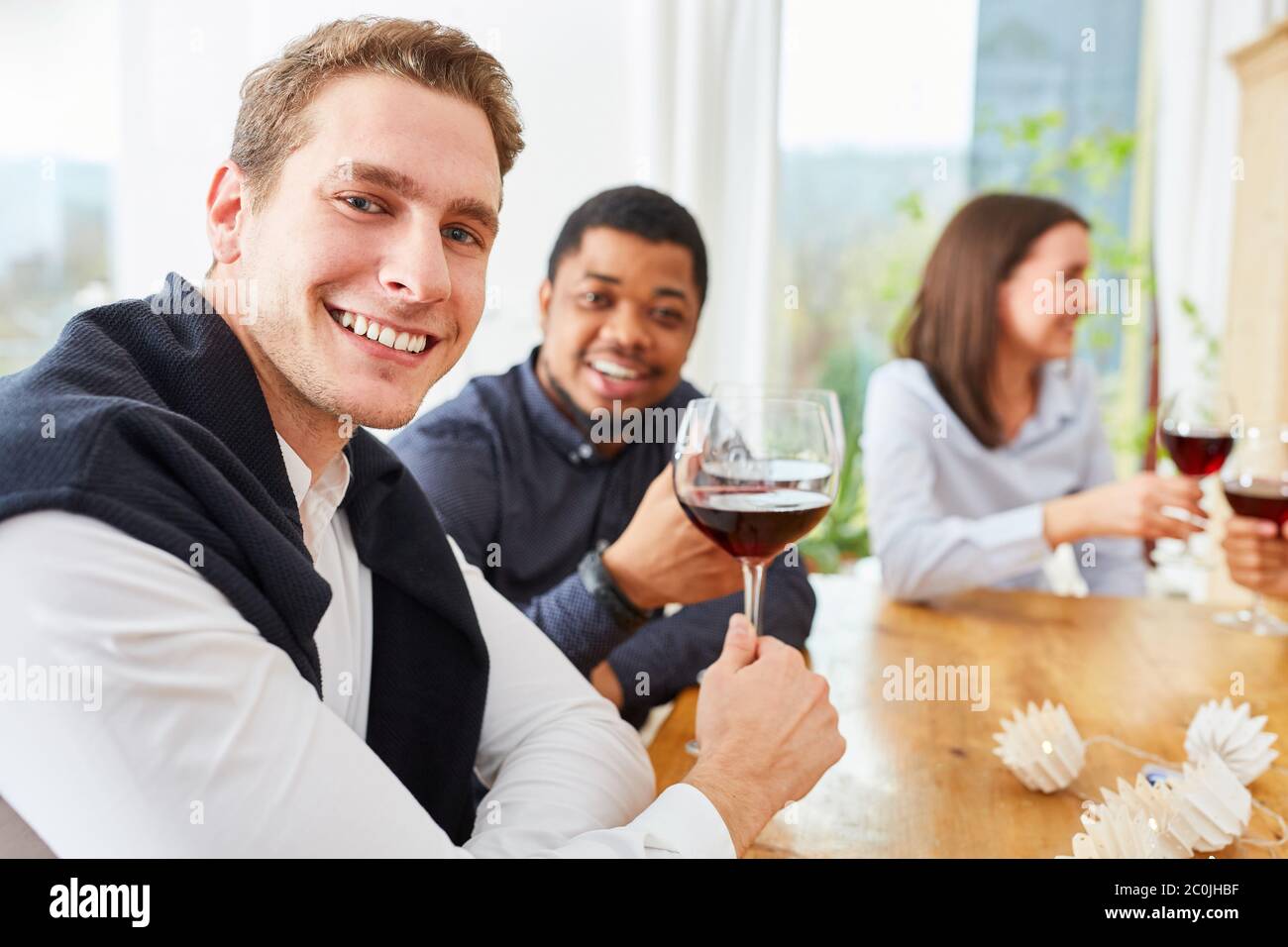 Les amis s'assoient à la table avec un verre de vin rouge et se rôtir Banque D'Images