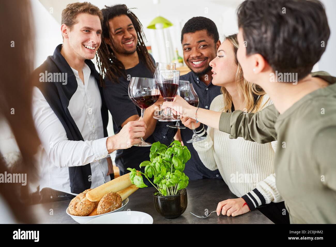 Un groupe d'amis heureux qui se fait griller avec un verre de vin rouge dans la cuisine Banque D'Images