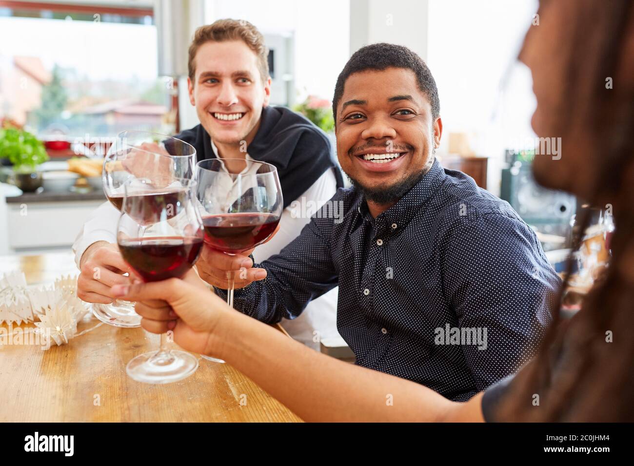Groupe d'hommes comme amis boire et de clinking des verres de vin dans une cuisine commune d'appartement Banque D'Images