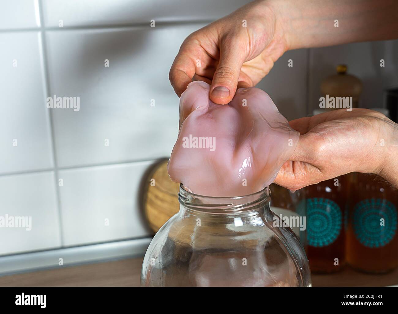 Champignon de thé Kombucha, mains tenant la pelle dans un pot en verre. Banque D'Images