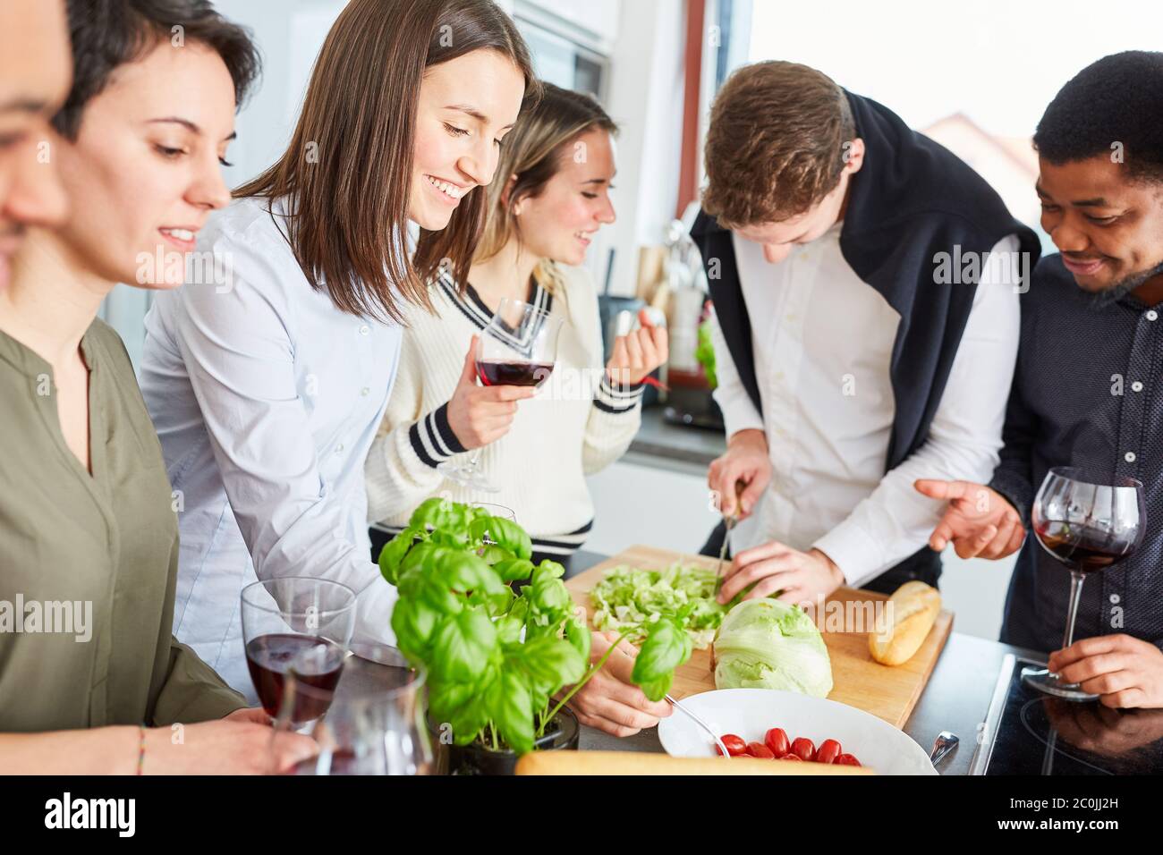 Groupe d'amis dans la cuisine de couper la salade pour un repas ensemble Banque D'Images