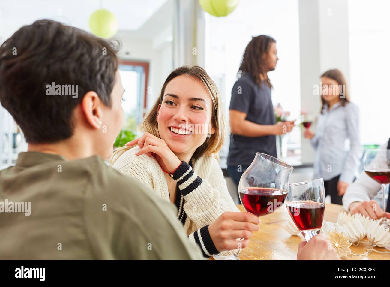 Deux femmes en tant qu'amis à une célébration toast avec un verre de vin rouge dans la cuisine Banque D'Images