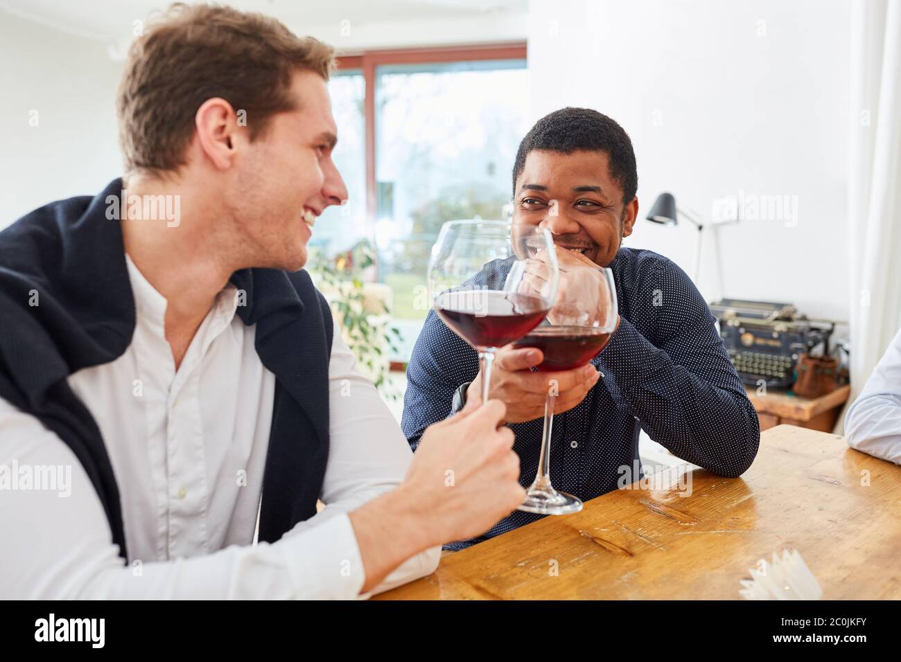 Deux hommes clinquent des verres de vin lors d'une fête d'anniversaire Banque D'Images