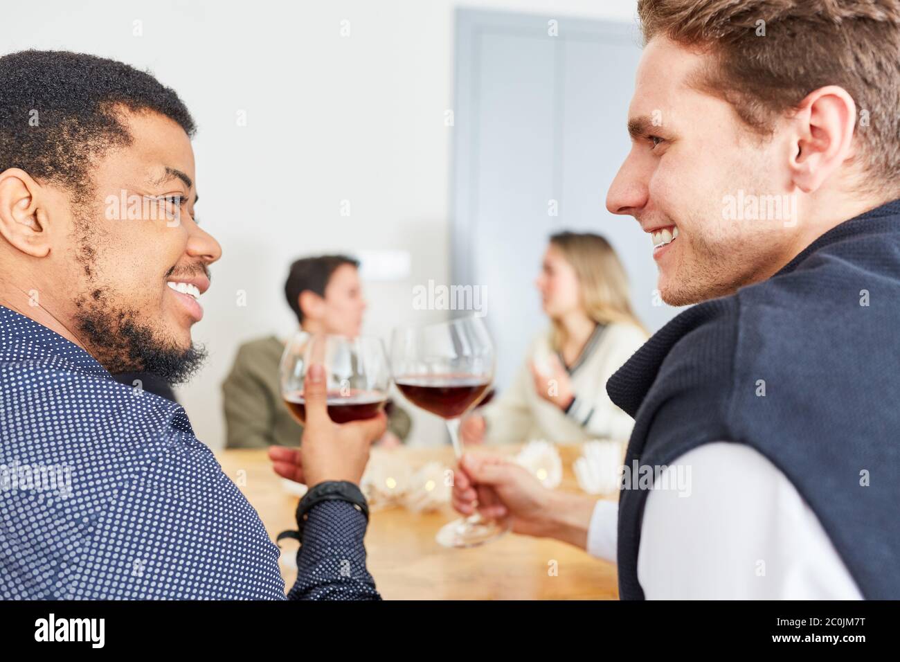 Deux hommes parlent et clink des verres de vin lors d'une fête d'anniversaire Banque D'Images