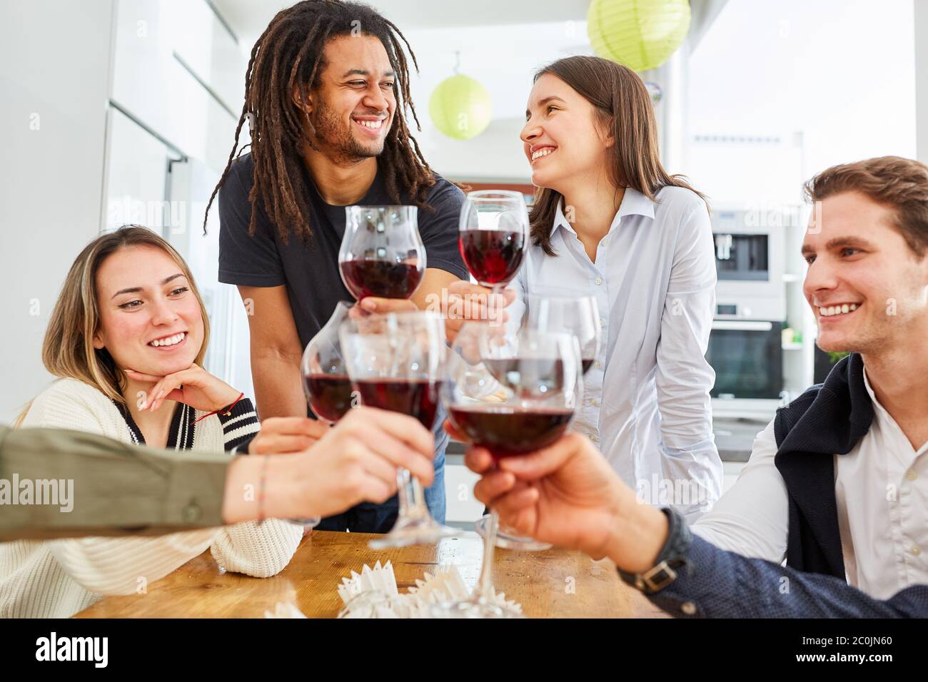 Un bon groupe d'amis pour fêter un toast dans la cuisine avec un verre de vin rouge Banque D'Images