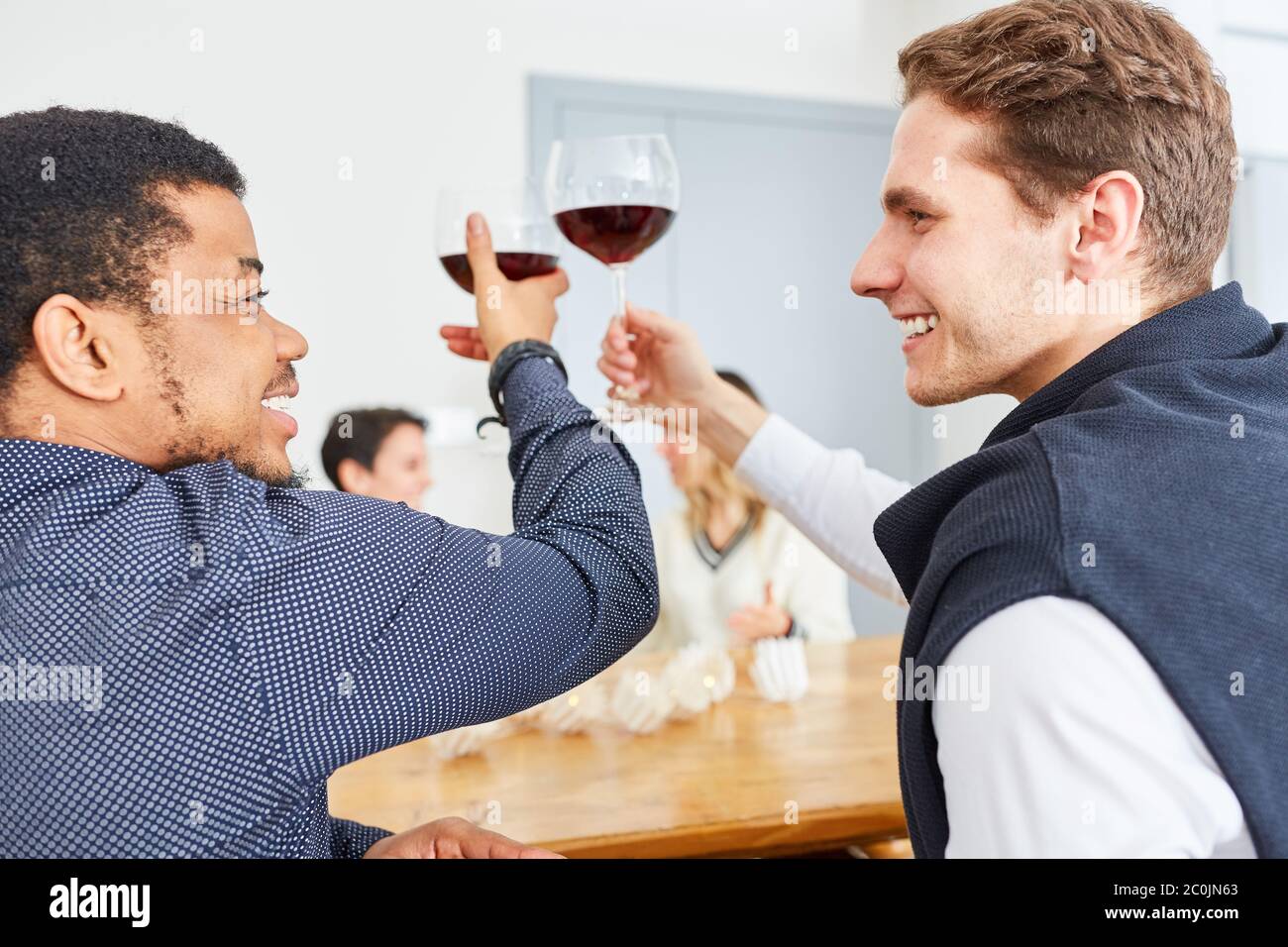 Deux hommes parlent et clink des verres de vin à une fête à la maison Banque D'Images