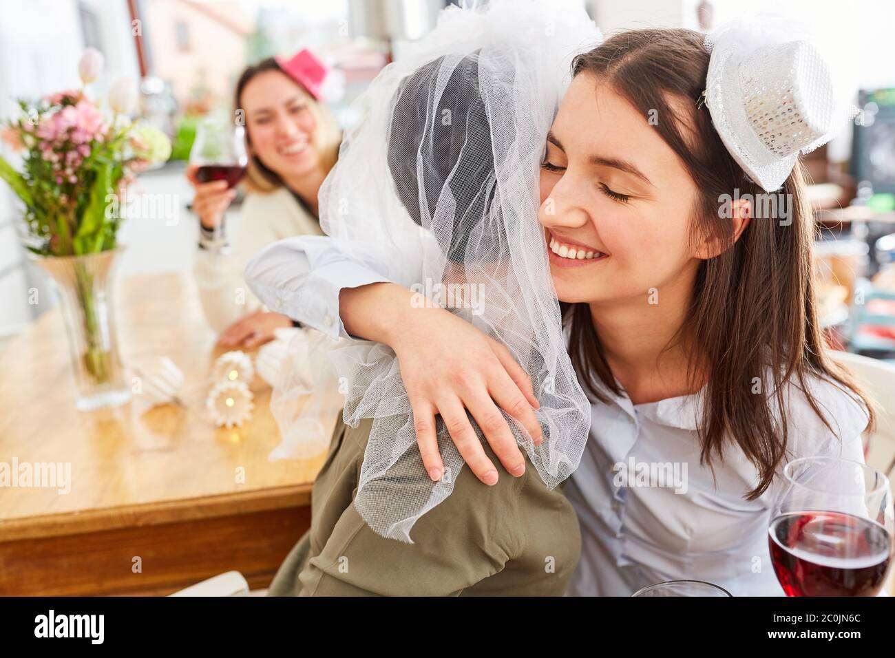 La petite amie félicite et épouse de câlins avec le voile de mariée sur la fête de poule Banque D'Images
