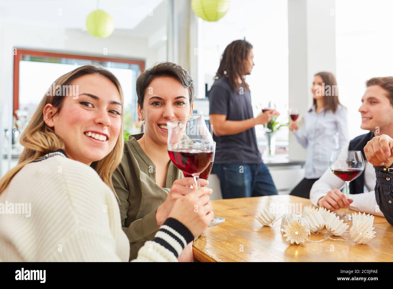 Deux femmes heureuses comme des amis toastent avec un verre de vin pour célébrer dans une cuisine Banque D'Images