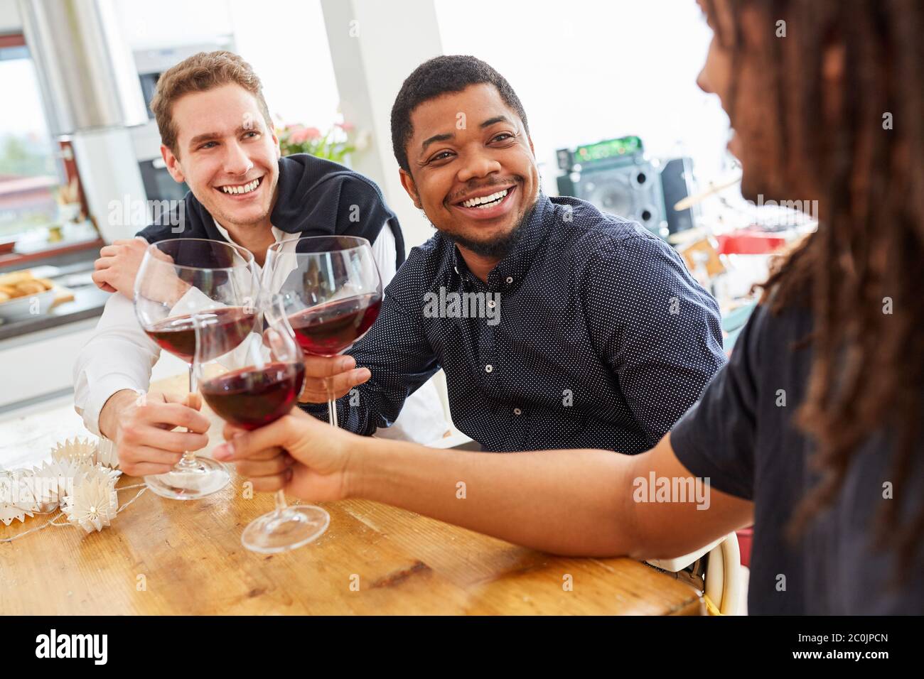 Groupe d'hommes joyeux comme amis clin des verres de vin dans une cuisine commune Banque D'Images