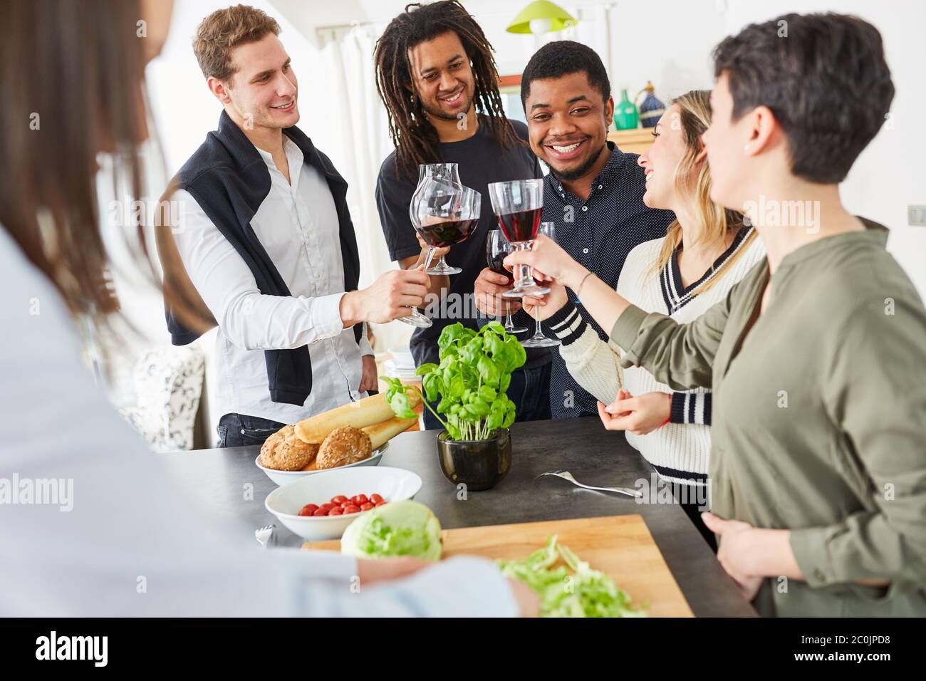 Un groupe d'amis heureux toast avec un verre de vin dans la cuisine avant de manger ensemble Banque D'Images