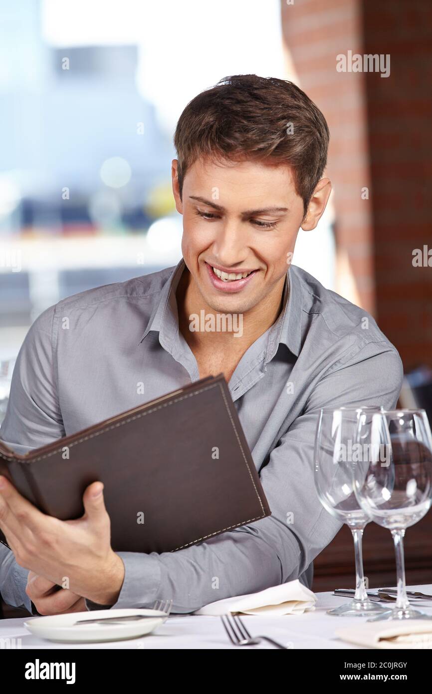 Un homme attrayant dans le restaurant regarde dans une carte de menu Banque D'Images