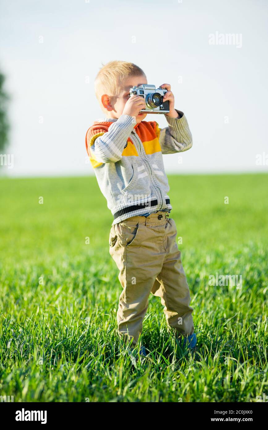 Petit garçon avec un ancien appareil photo shooting en extérieur. Banque D'Images