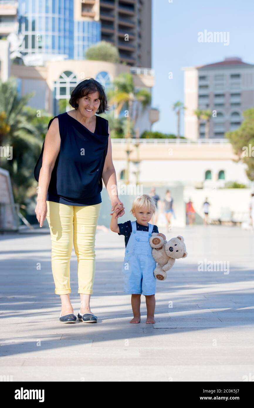 Enfant Mignon Petit Garcon Et Grand Mere Main Dans La Main Dans La Ville Bebe Tenant L Ours En Peluche Souriant A L Appareil Photo Photo Stock Alamy