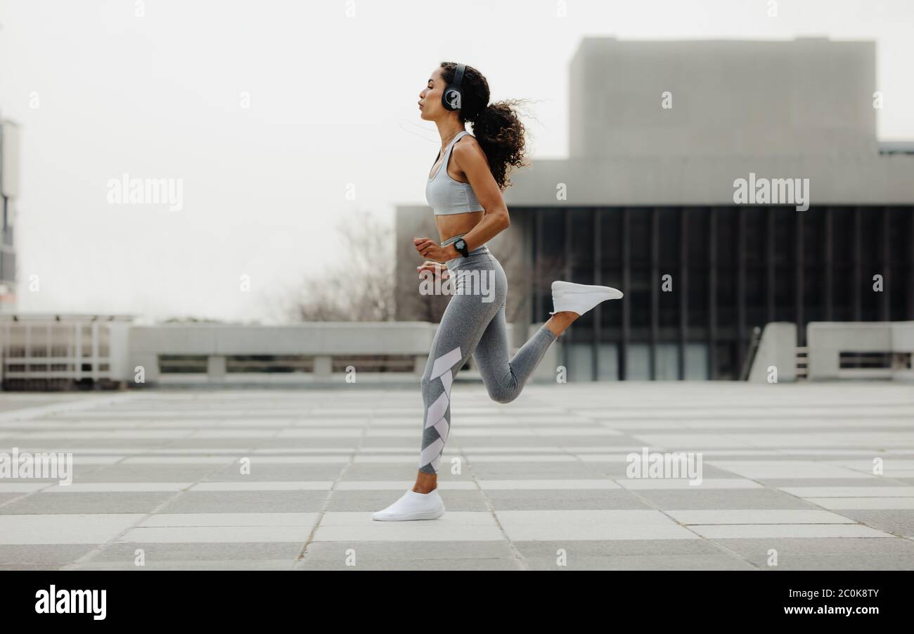 Photo en pleine longueur d'une femme en bonne santé qui court dans la ville. Femme sportive s'exerçant dans la ville. Banque D'Images