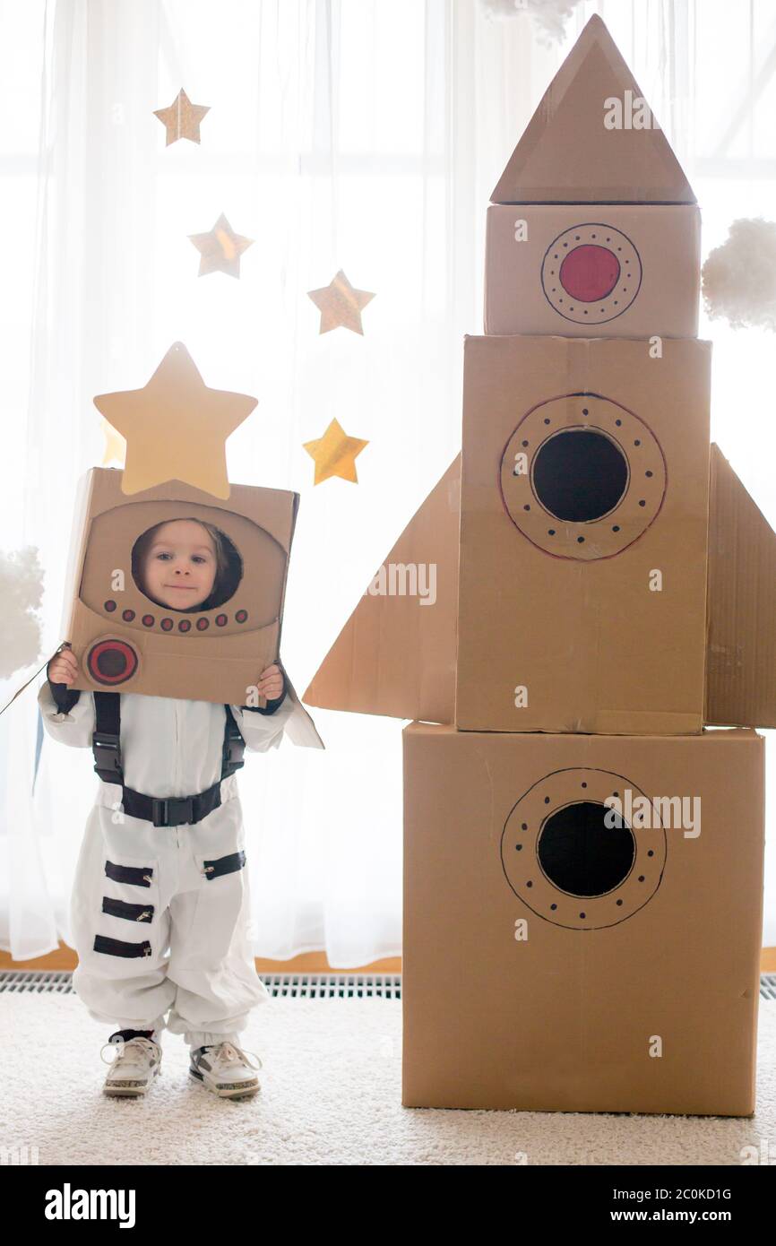 Un adorable petit garçon, habillé comme un astronaute, jouant à la maison  avec une fusée en carton et un casque fait main de la boîte Photo Stock -  Alamy