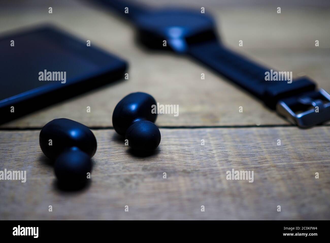 Vue rapprochée d'un téléphone portable intelligent, d'écouteurs sans fil et d'une montre intelligente sur une table en bois Banque D'Images