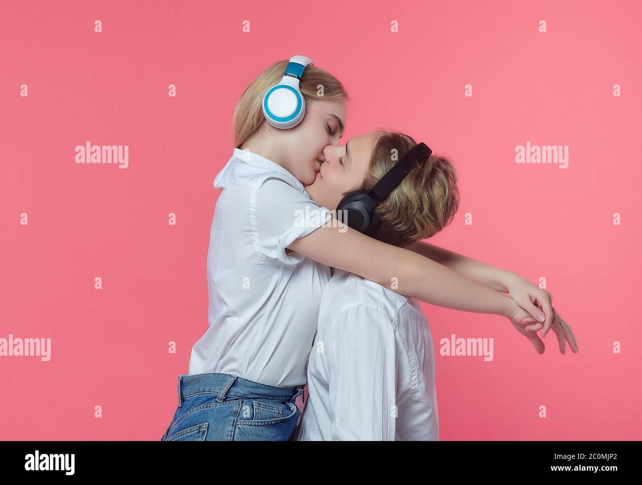 guy et fille dans un casque. écoutez de la musique tout en exprimant des émotions avec un baiser. dos rose Banque D'Images
