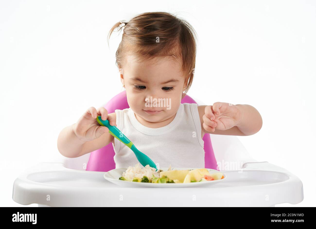 Bébé fille essayant de nouveaux aliments isolés sur fond blanc studio Banque D'Images