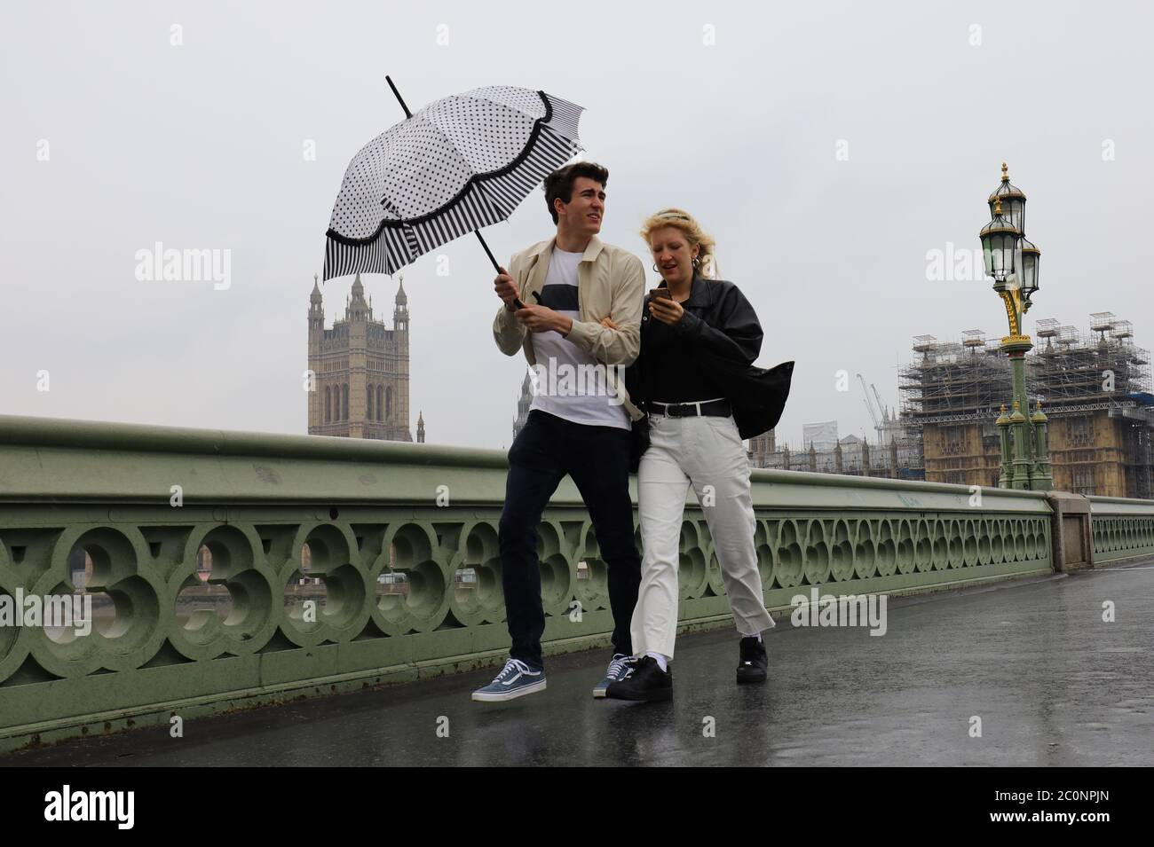 Un couple marche à travers le pont de Westminster, Londres sous la pluie. Banque D'Images