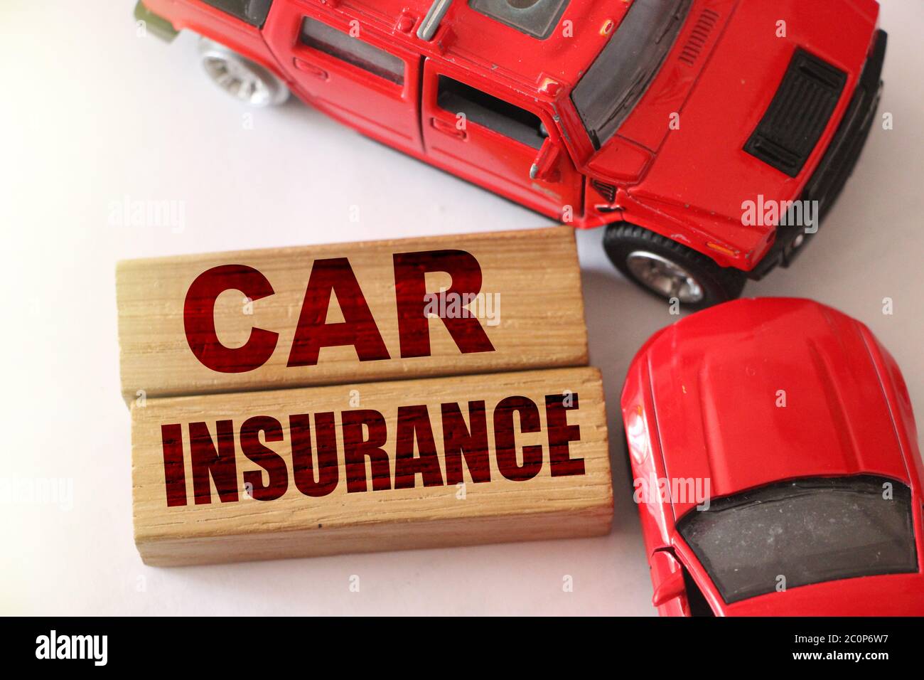 Mots d'assurance automobile sur des blocs de bois et deux voitures rouges dans un accident de la route sur fond blanc. Concept d'assurance Banque D'Images