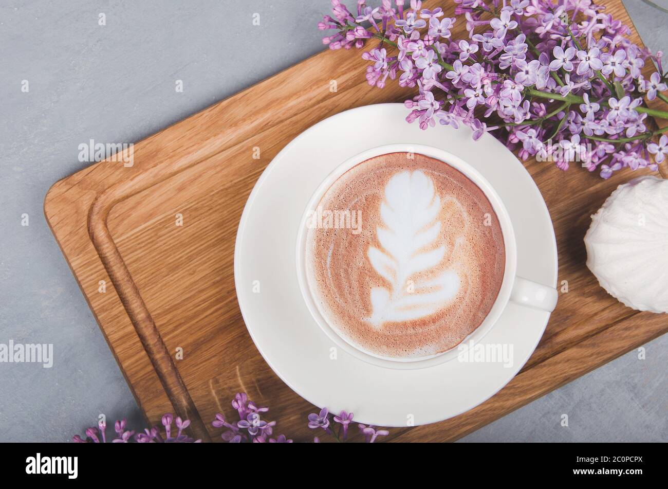 Lilas, café avec latte art sur table en bois gris. Matin romantique. Pose à plat Banque D'Images