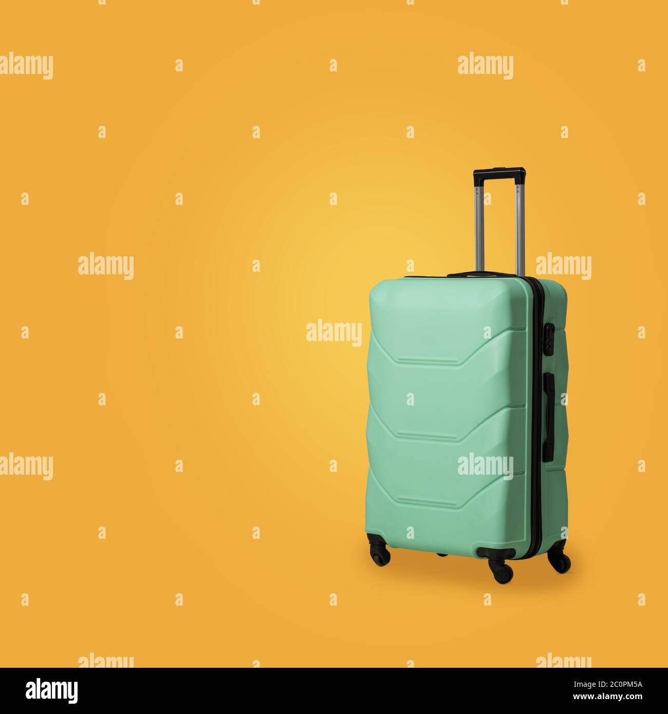 Valise en plastique vert avec roulettes isolées sur fond jaune ensoleillé. Étui en polycarbonate vert menthe pour ranger vos bagages en toute sécurité. Vide ou modèle Banque D'Images