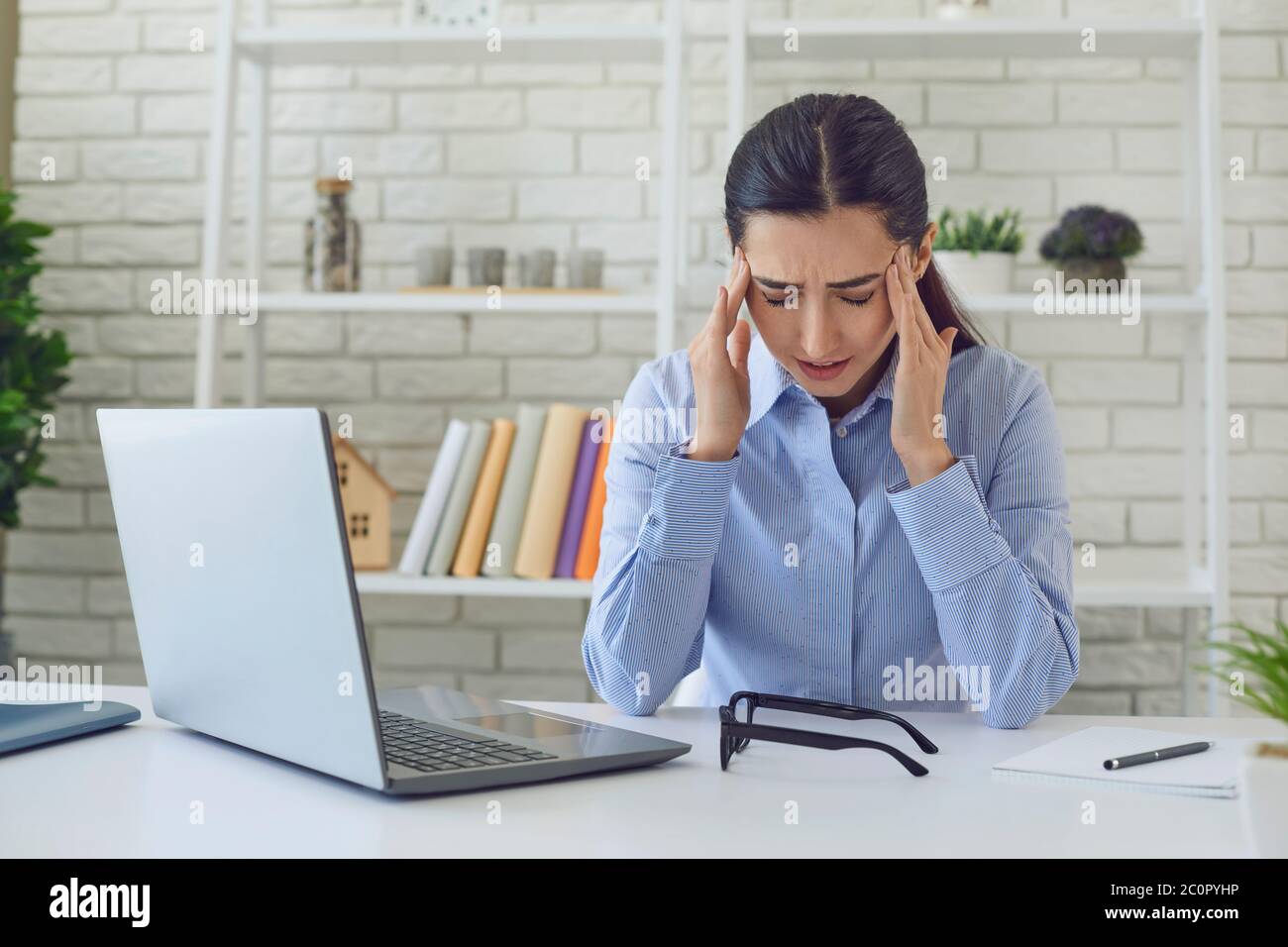 Femme avec mal de tête. Femme professionnelle au bureau à domicile avec ordinateur portable ayant mal de tête en raison du stress de travail. Banque D'Images