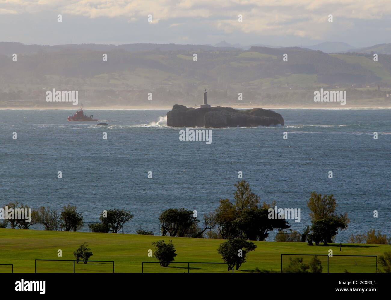 Isla del Mouro ou l'île de Moors avec le garde-côtes rouge Bateau passant sur son chemin vers la mer Santander Cantabria Espagne Banque D'Images