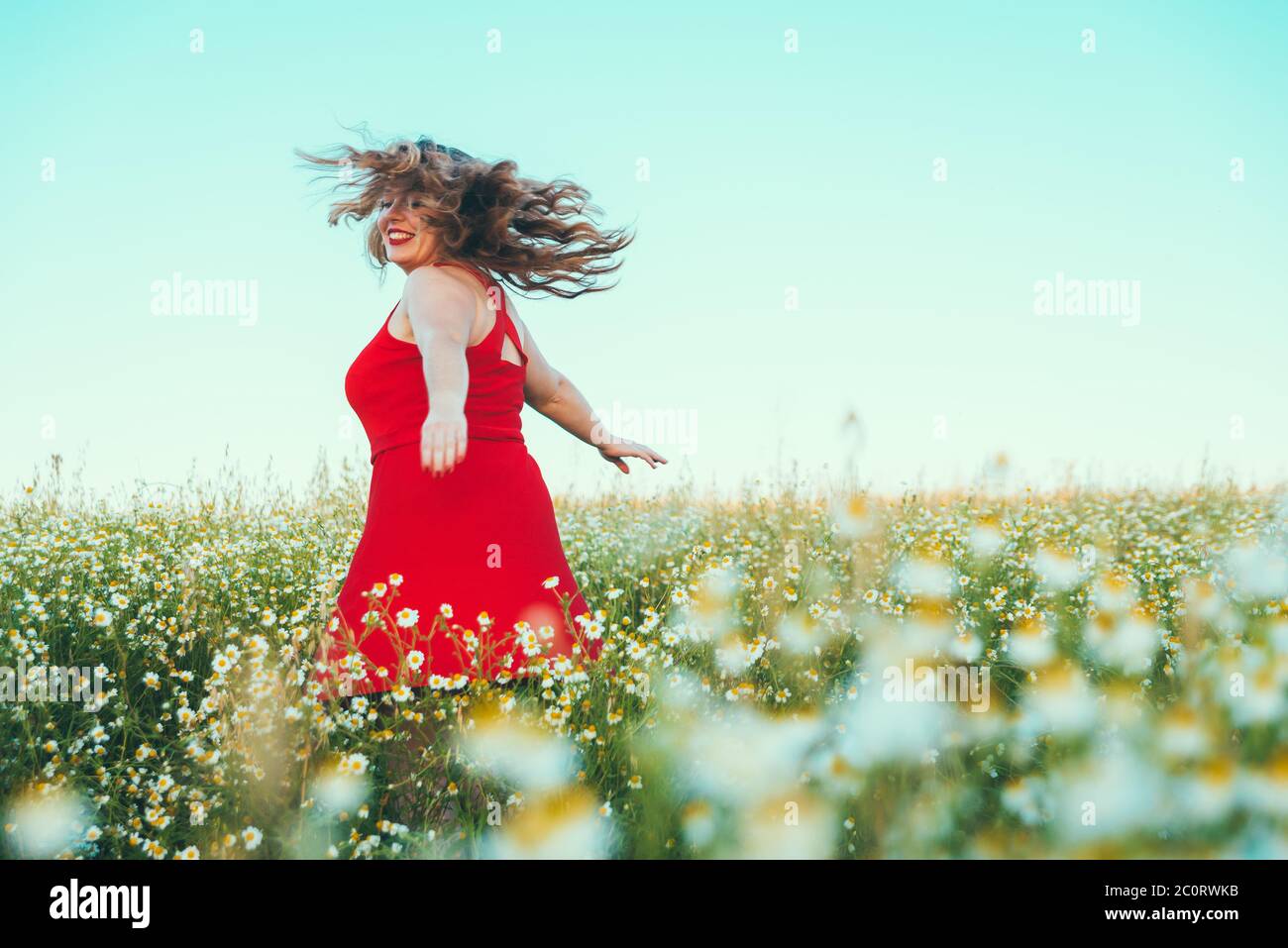 femme blonde avec robe rouge tournant dans le champ Banque D'Images