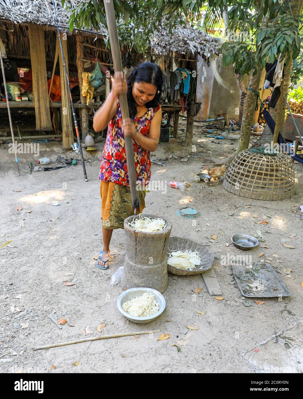 Une femme qui a frappé ou frappé des oignons dans une casserole avec un poteau dans un petit village près du complexe du temple d'Angkor Thom, Siem Reap, Cambodge, Asie Banque D'Images