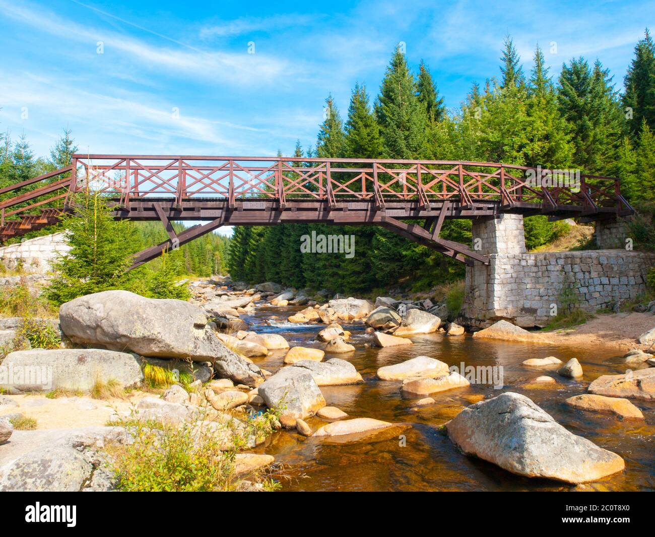 Pont piétonnier en bois sur la rivière Jizera, plein de rochers en granit. Frontière entre Jizerka et le village d'Orle dans les montagnes de Jizera, République tchèque, Pologne. Banque D'Images