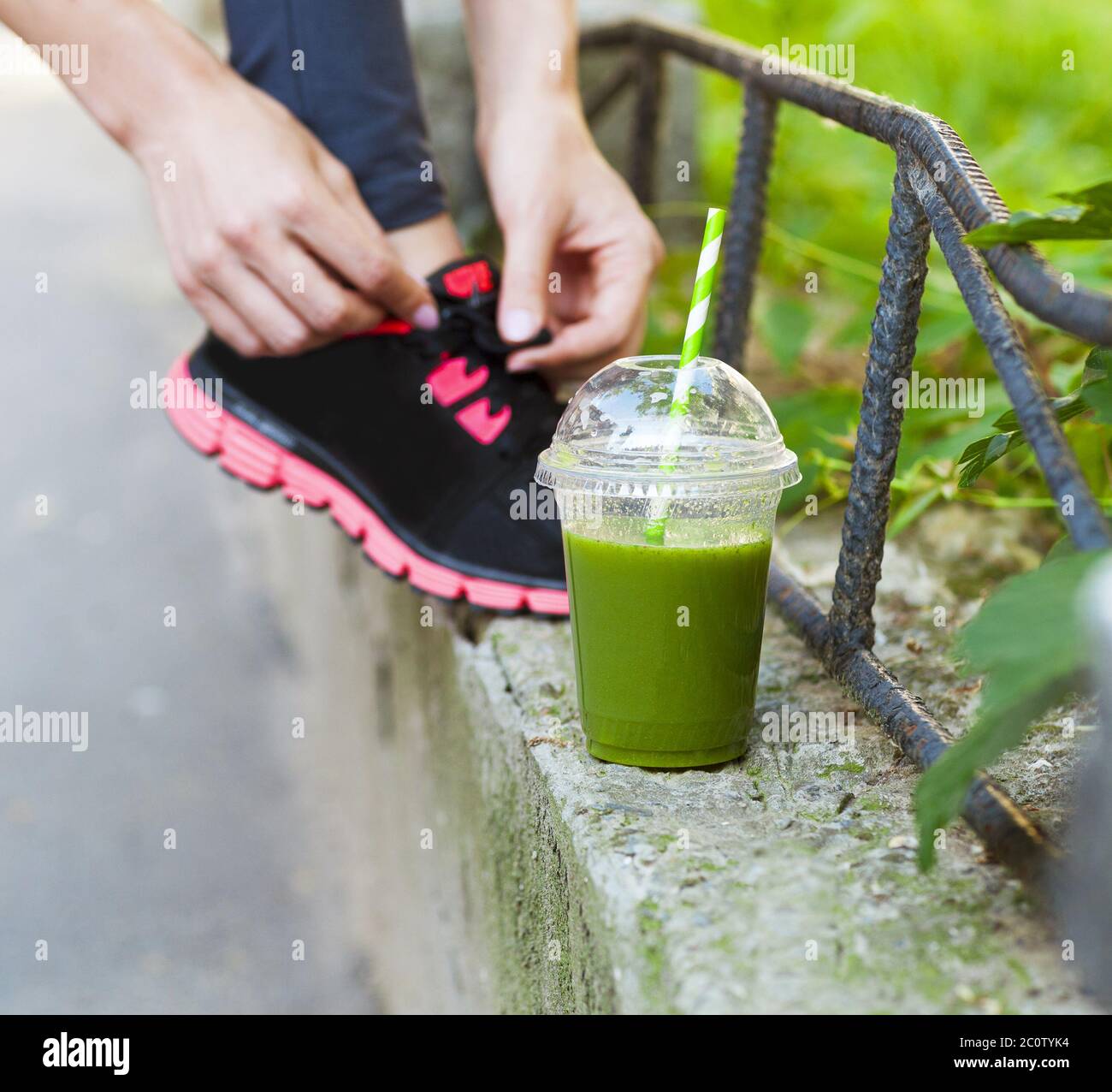 Coupe smoothie Detox verte et femme laçage des chaussures de course avant l'entraînement Banque D'Images