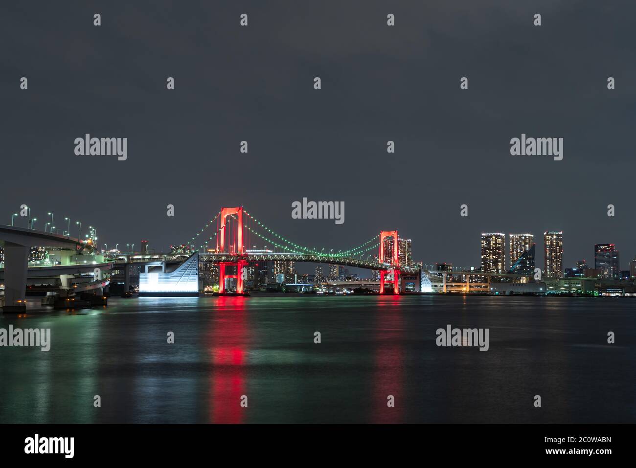 Vue nocturne du pont Rainbow, illuminé en rouge comme un signe de 'Tokyo Alert (alerte de coronavirus pour la région de Tokyo)' à Odaiba, Japon. Banque D'Images