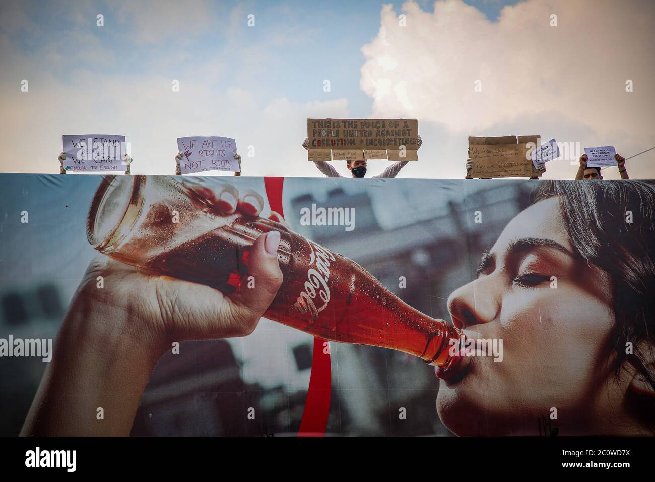 Les manifestants tiennent des pancartes derrière un panneau d'affichage au cola de coca à Pulchowk pendant la manifestation. Pour la troisième journée consécutive, une protestation népalaise contre le gouvernement ? Mauvaise gestion de la crise COVID-19 par manque de transparence et de corruption, ils remettent en question la compétence du gouvernement KP Oli et leur mauvaise utilisation de l'argent des contribuables. Banque D'Images