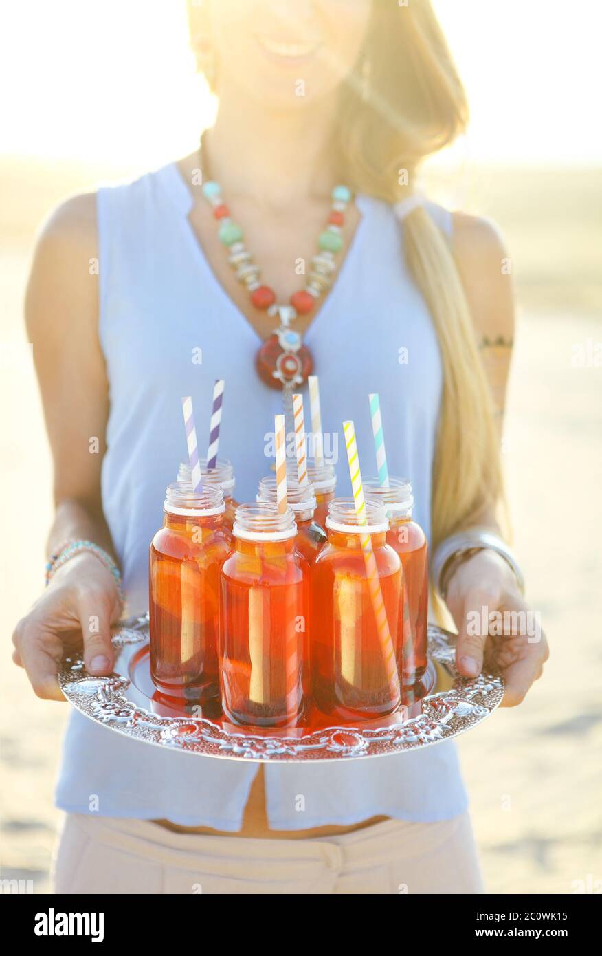 Bonne jeune femme tenant un plat avec un verre à la fête du coucher du soleil Banque D'Images