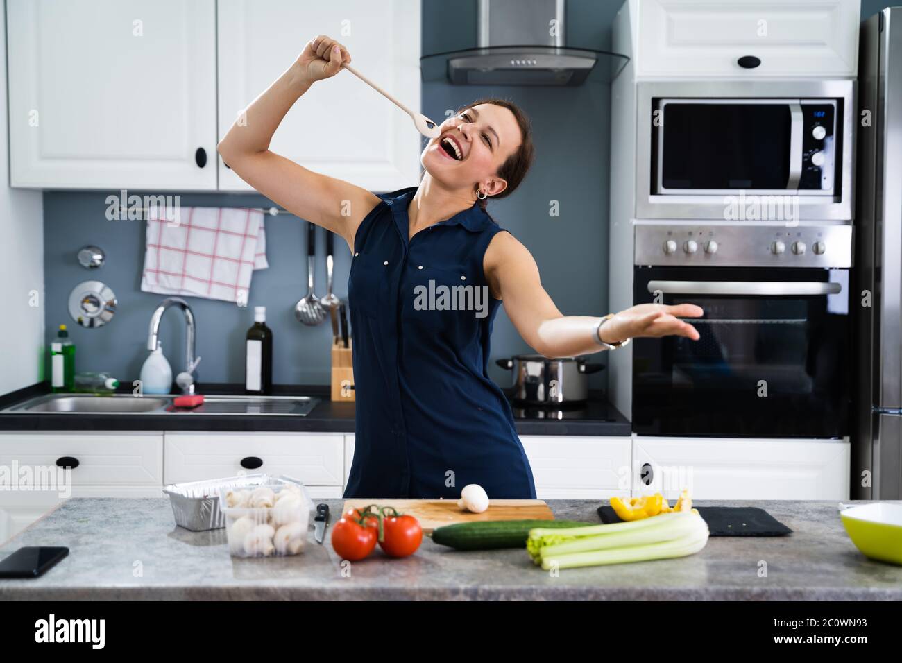 Femme dansant et chantant en cuisine Banque D'Images