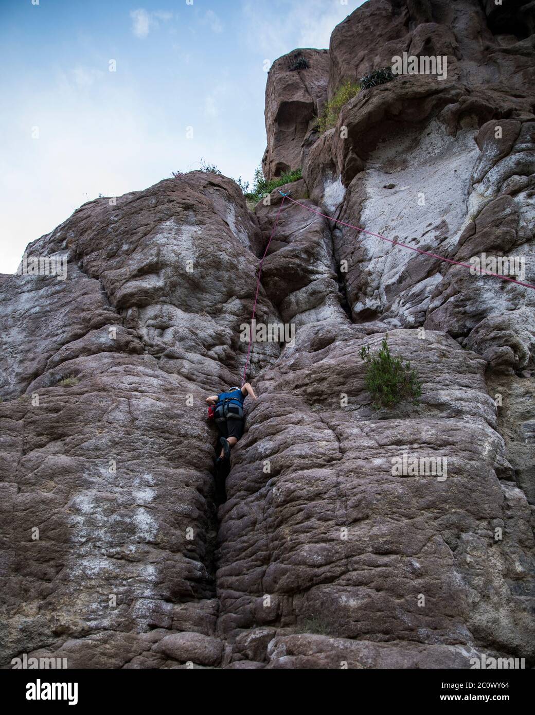 femme grimpant sur une montagne rocheuse, avec harnais et casque Banque D'Images