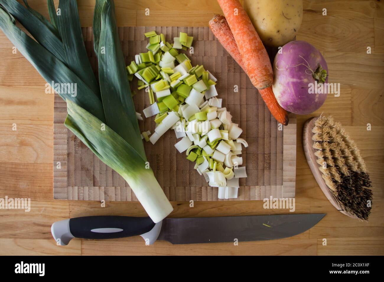 Vue de dessus d'une planche à découper, légumes d'hiver, brosse et couteau sur une table en bois Banque D'Images