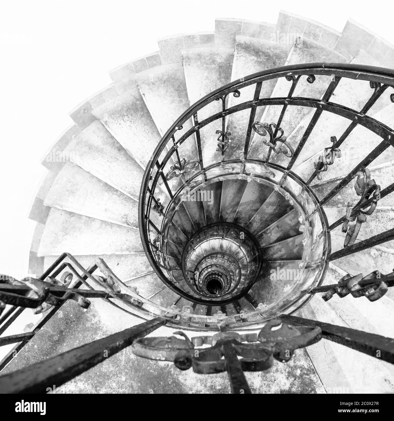 Vue à l'envers de l'escalier intérieur en spirale avec main courante décorative en métal noir. Détails architecturaux à la basilique Saint-Étienne de Budapest, Hongrie. Image en noir et blanc. Banque D'Images